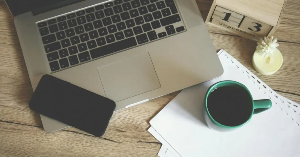 A minimalist workspace with coffee and a laptop, symbolizing the ease of sending a formal leave application from home.