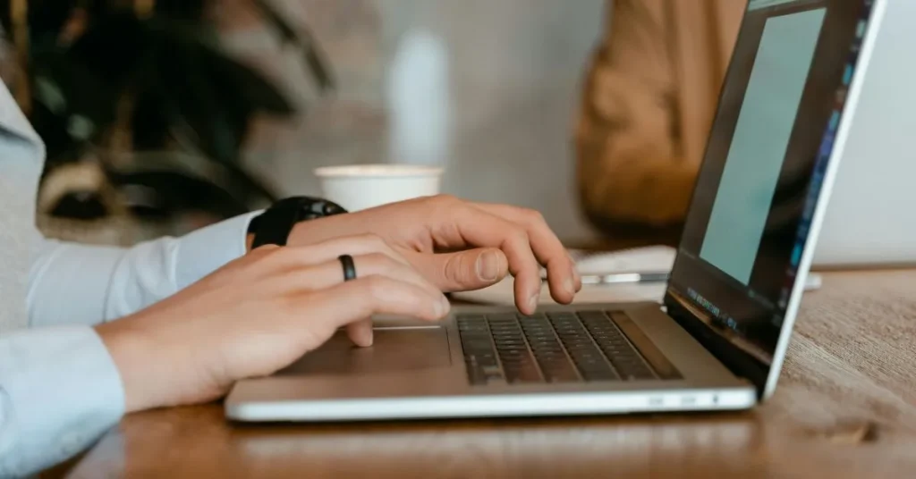 Close up of hands typing a professional apology email on a laptop to restore business trust.